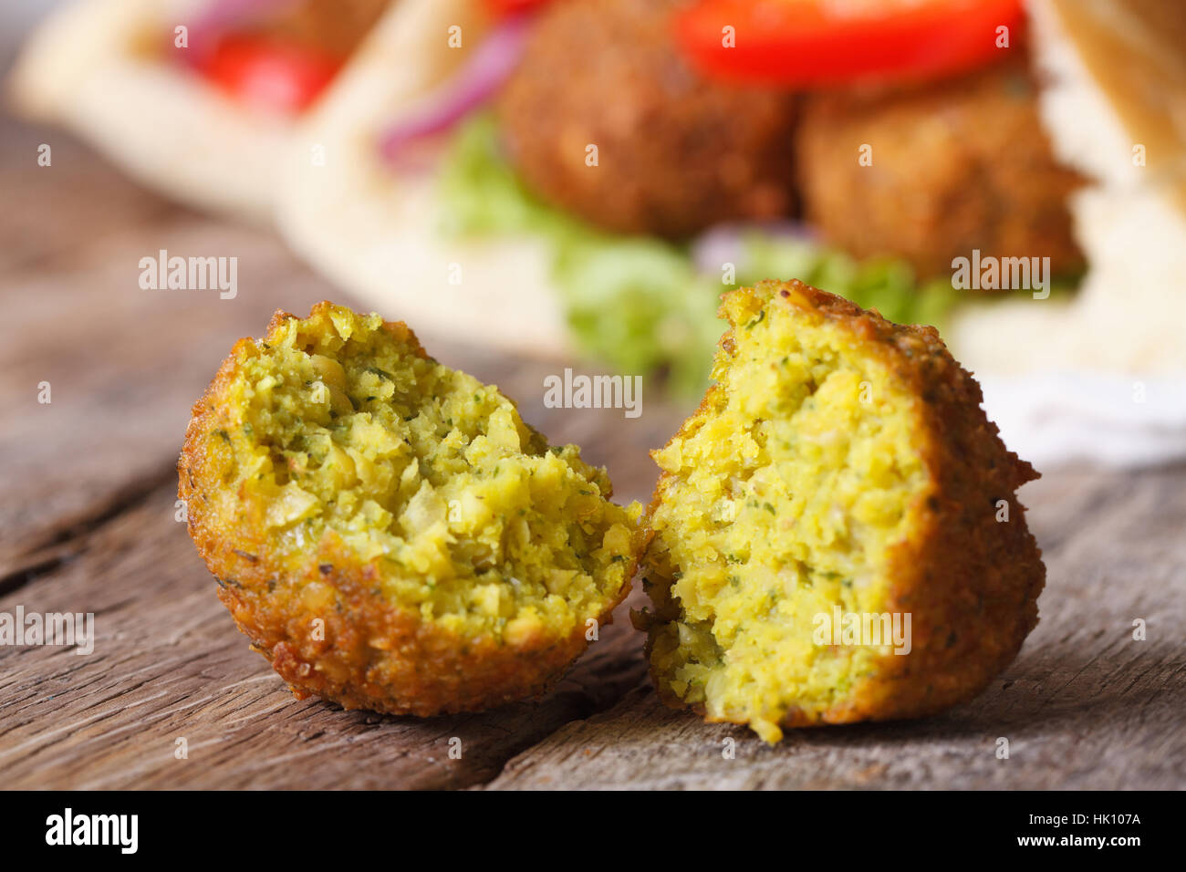 falafel macro on an old wooden table against the background of pita bread with vegetables horizontal Stock Photo