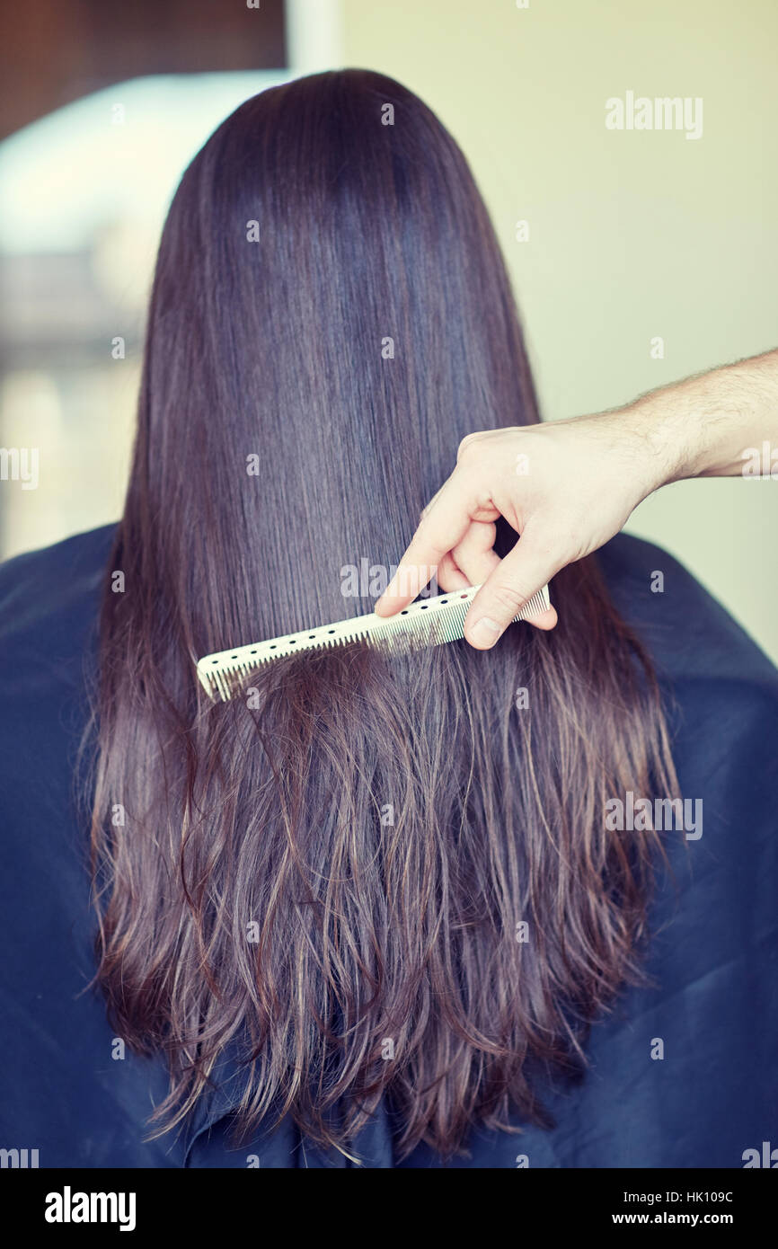 hand with comb combing woman hair at salon Stock Photo