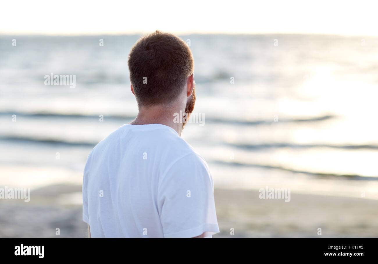 young man in white t-shirt on beach looking at sea Stock Photo - Alamy