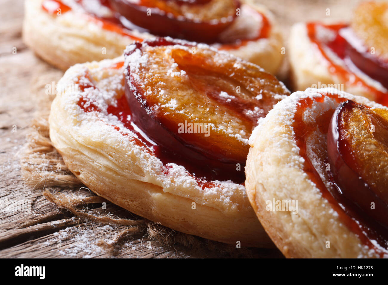 Pies of puff pastry with plums macro on an old table. horizontal Stock Photo