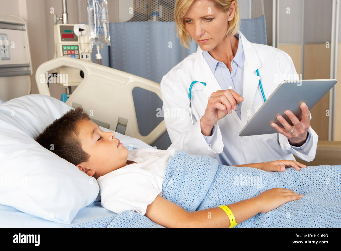 Doctor Using Digital Notepad Whilst Visiting Child Patient Stock Photo