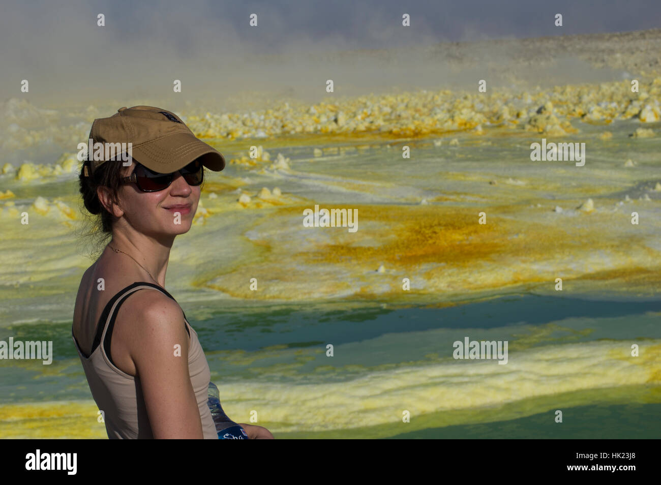 Woman in hat and sunglasses at Dalol, Danakil Depression, Ethiopia and the vivid yellows and green of the strange crystal shapes Stock Photo