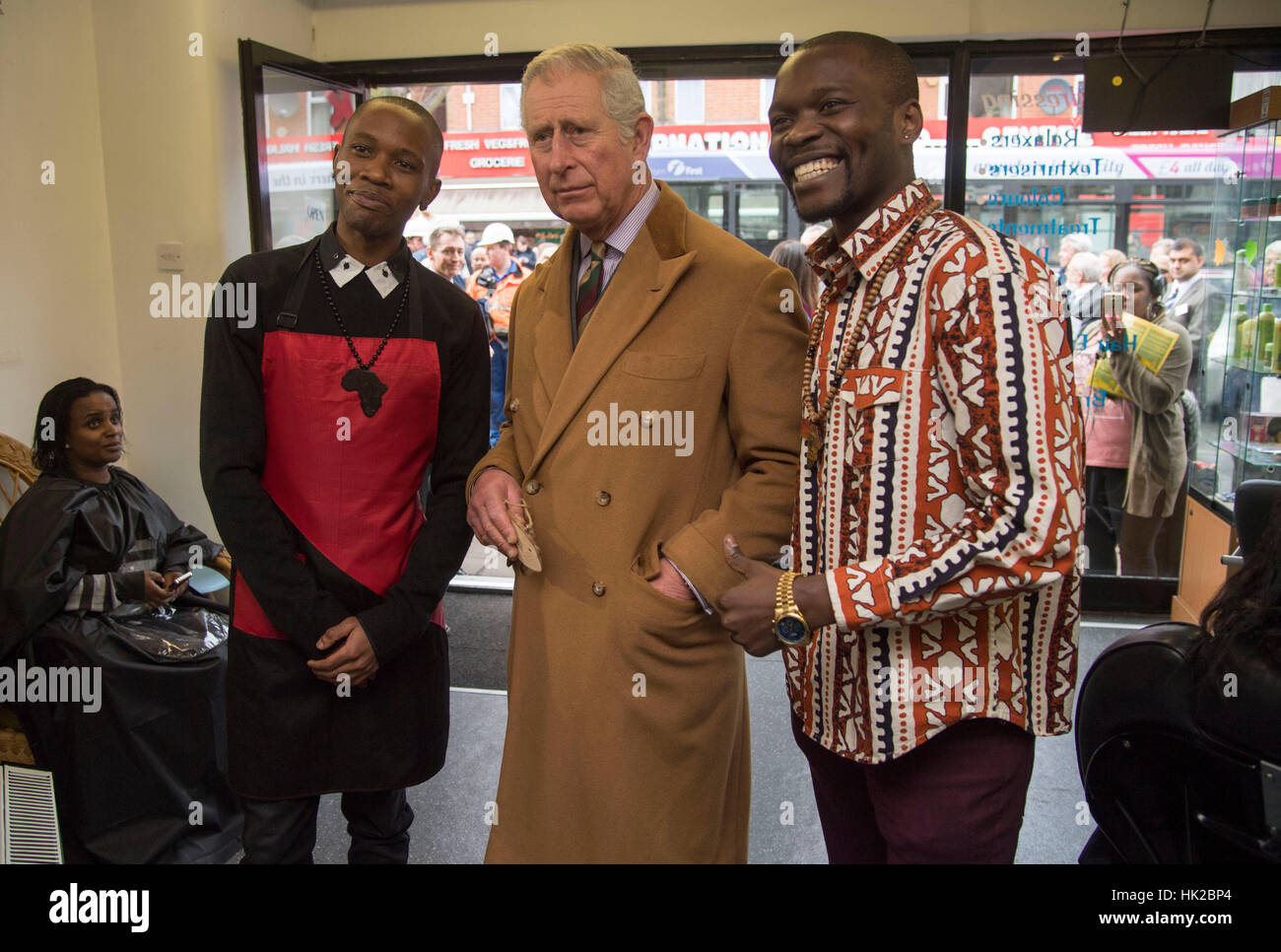 The Prince of Wales poses for a photo inside a hairdresser's shop during a visit to businesses
