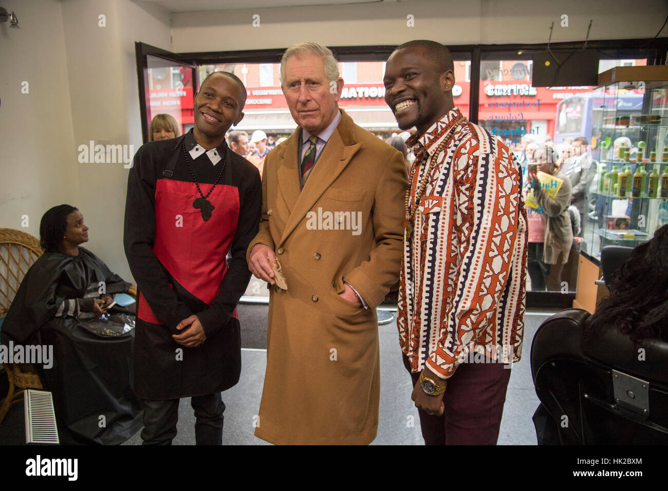 The Prince of Wales poses for a photo inside a hairdresser's shop during a visit to businesses