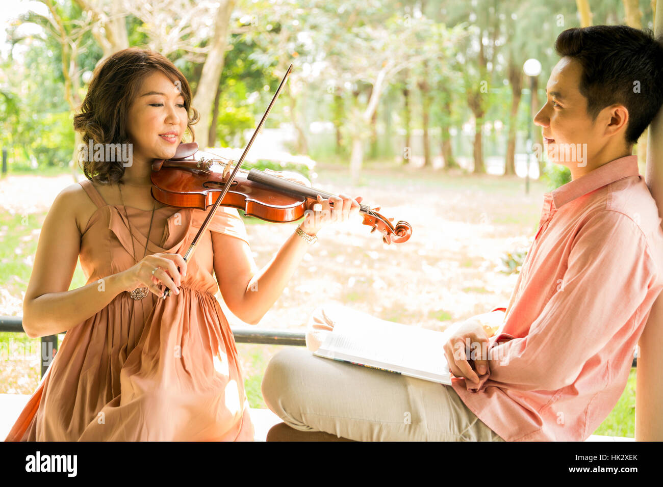 Young woman playing violin with her boyfriend in garden Stock Photo - Alamy