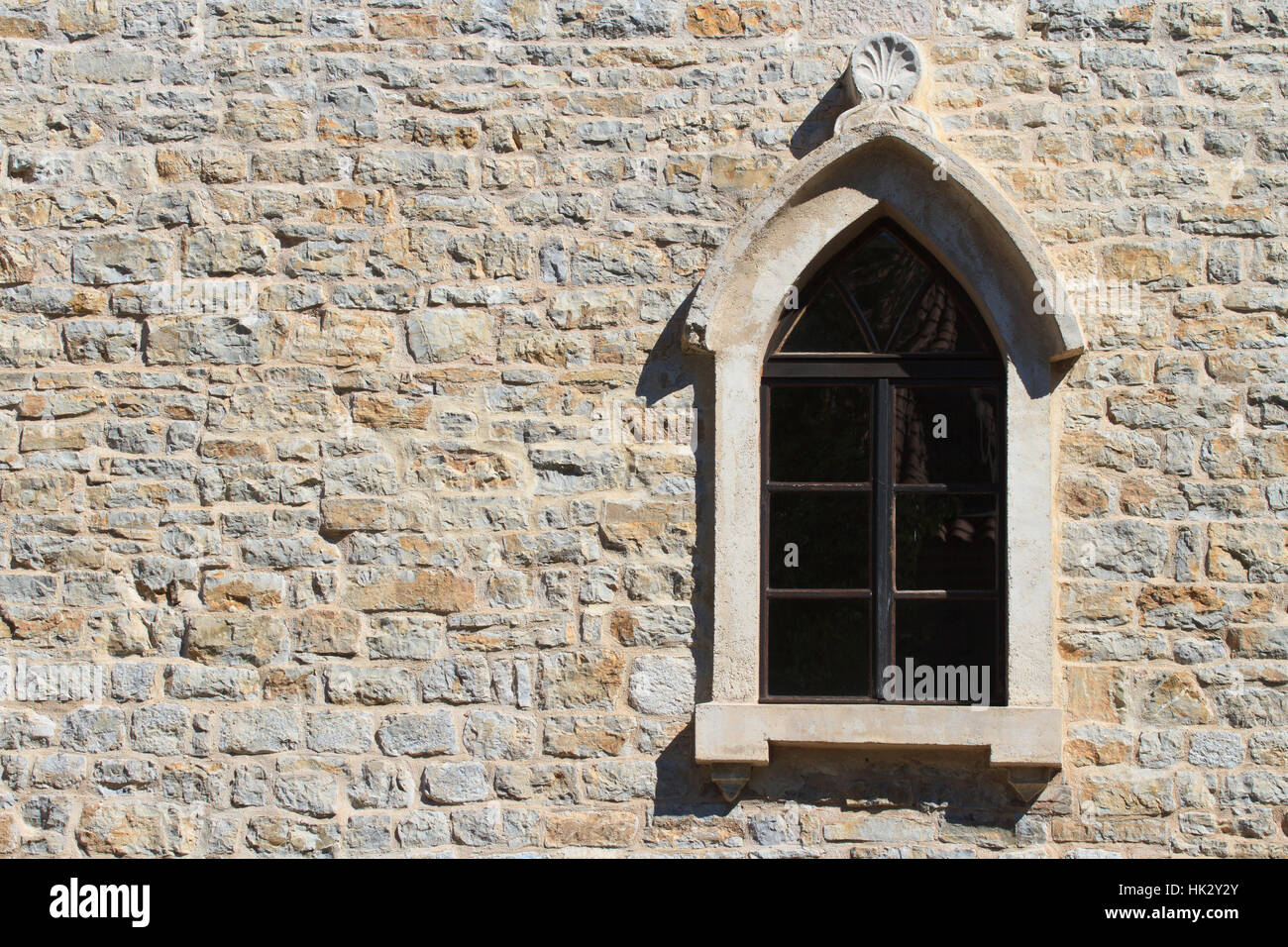 Window with an arch on the old wall in the city of Budva. Montenegro Stock Photo