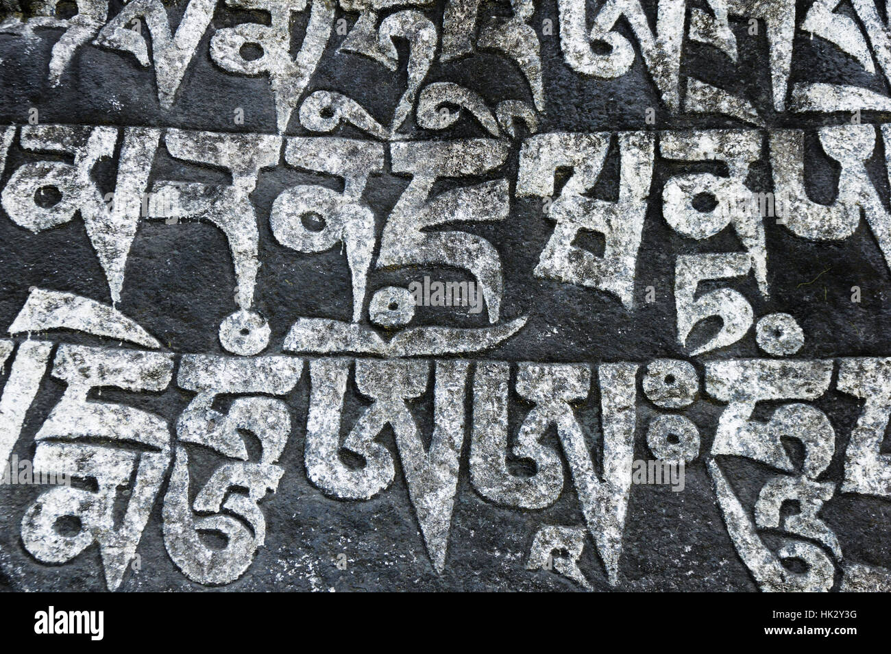 Mani stone carved with Tibetan script and painted white and black Stock Photo