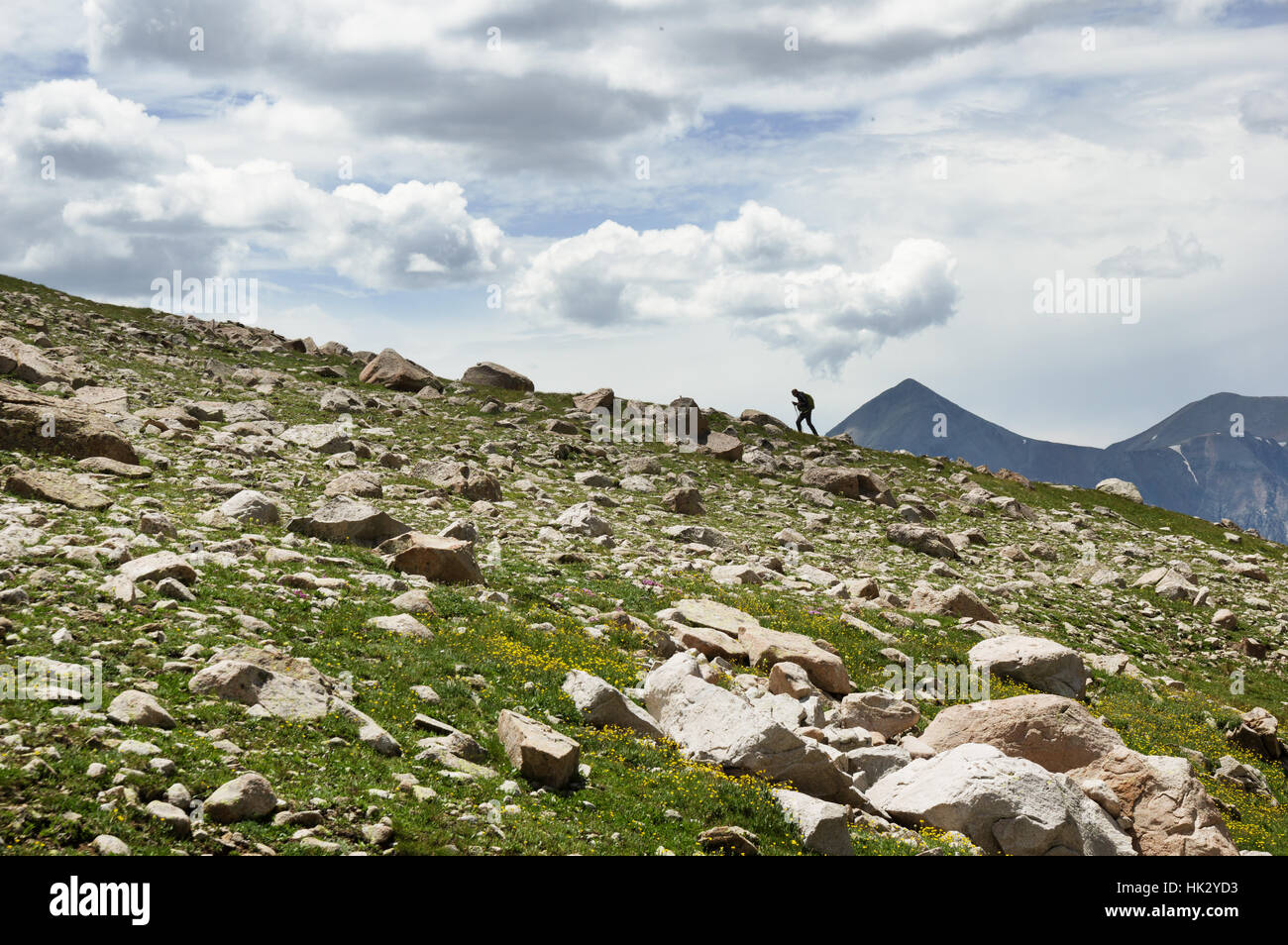 distant woman hiking up a ridgeline in the San Juan Mountains of Colorado Stock Photo