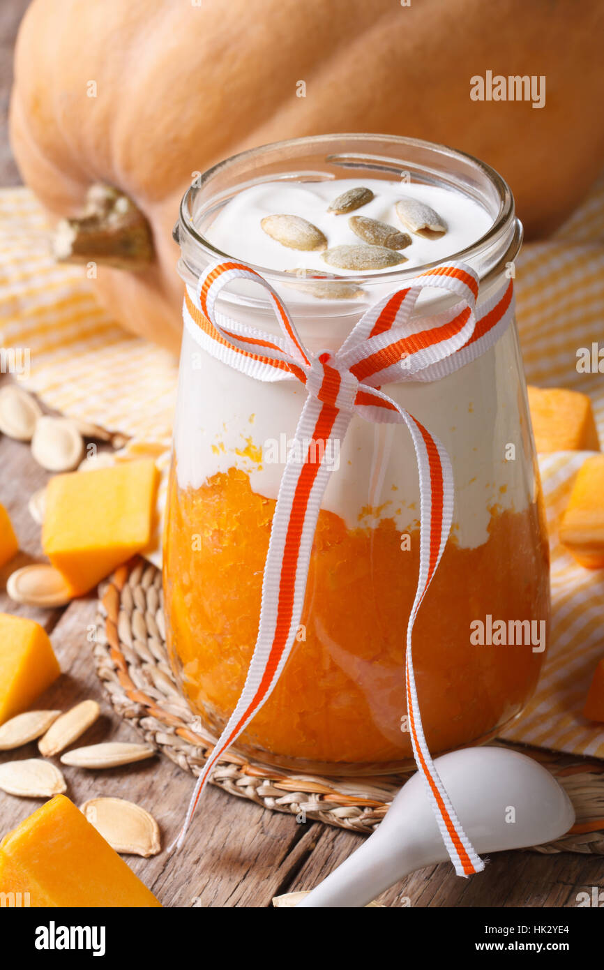 dessert of pumpkin, cream and seeds in a jar closeup. vertical Stock Photo