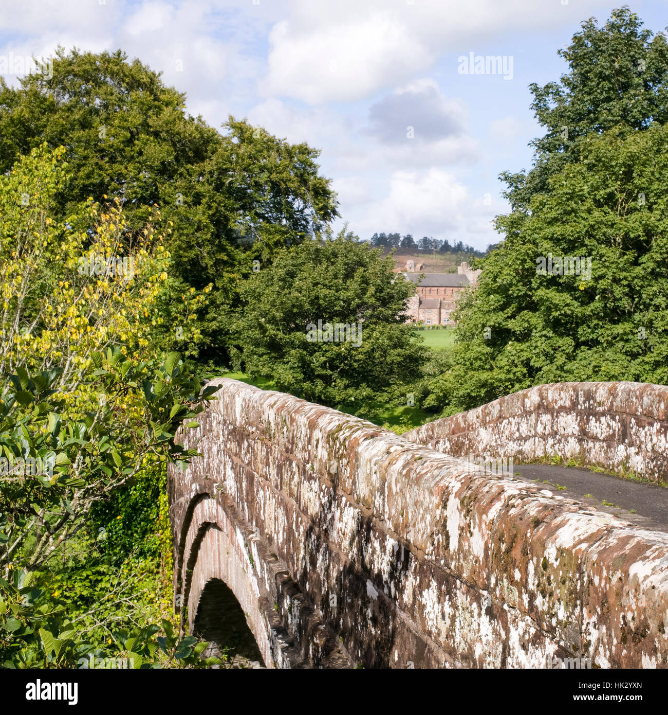 The old bridge (1724) at Lanercost with the Priory in distant view, Brampton, Cumbria, England, UK Stock Photo
