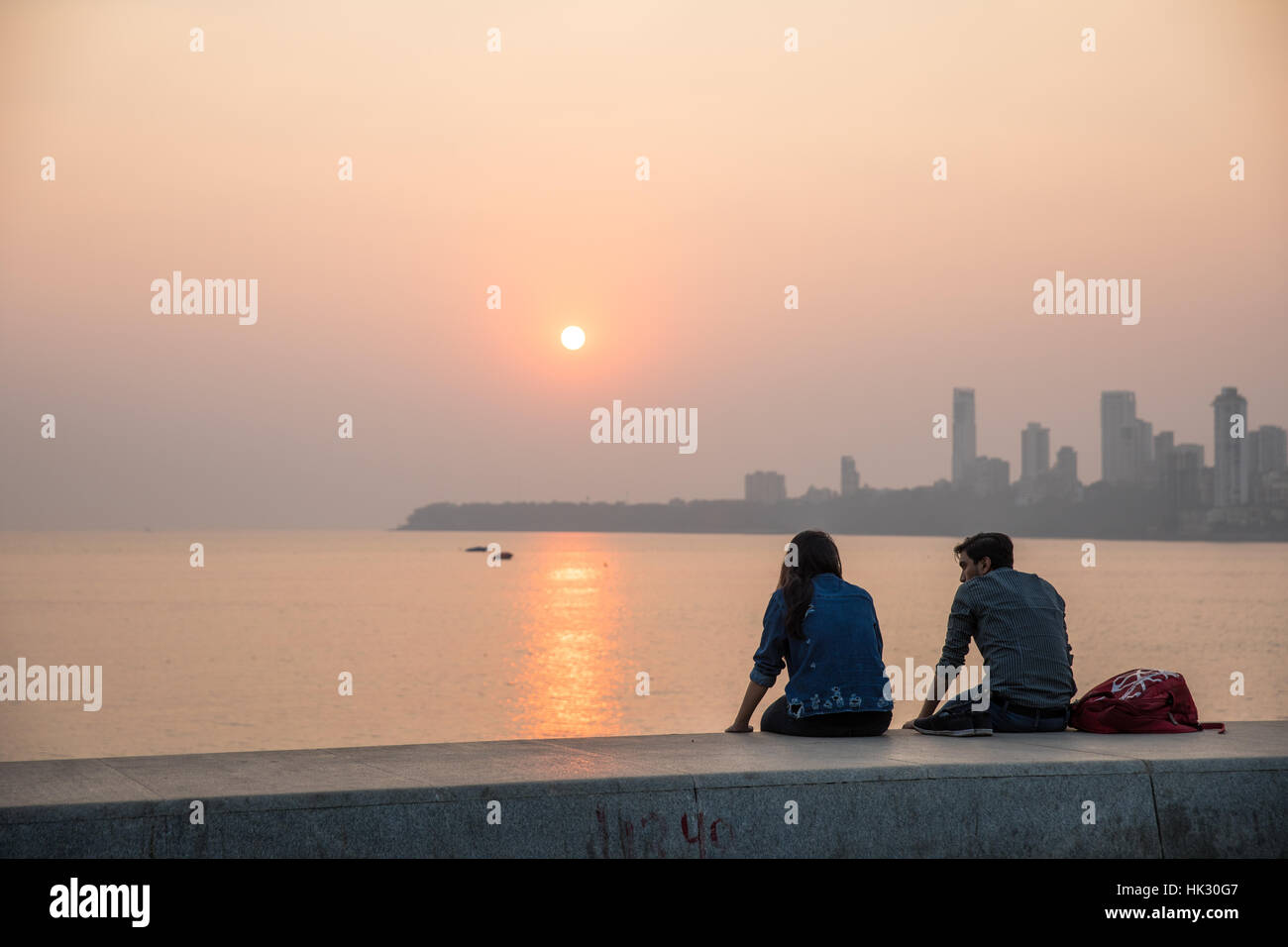 Couples watch the sunset over Chowpaty Beach in Mumbai (Bombay), India. Stock Photo