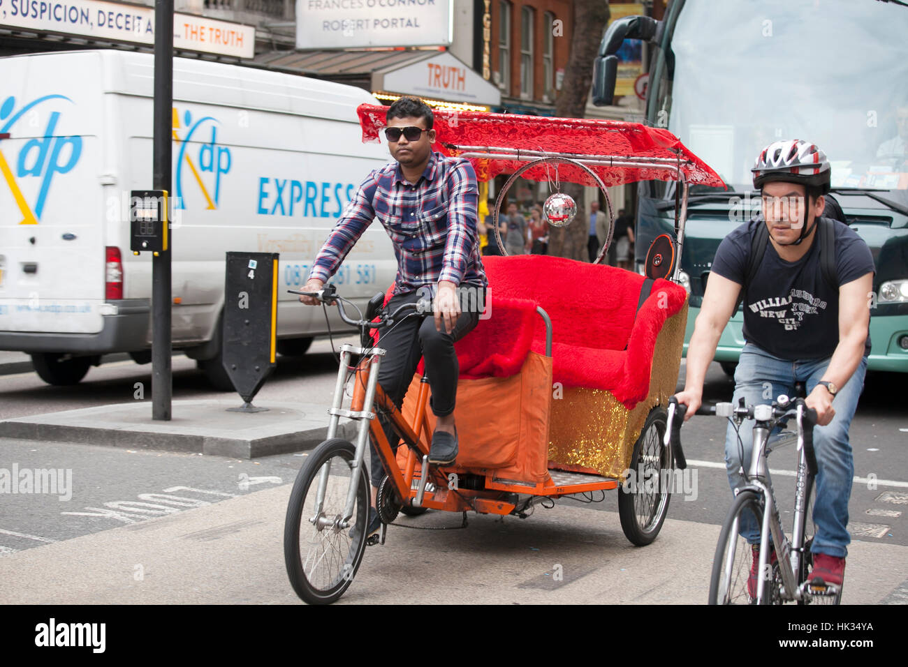 LONDON, ENGLAND - JULY 12, 2016 trishaw and cyclist riding on the road Stock Photo