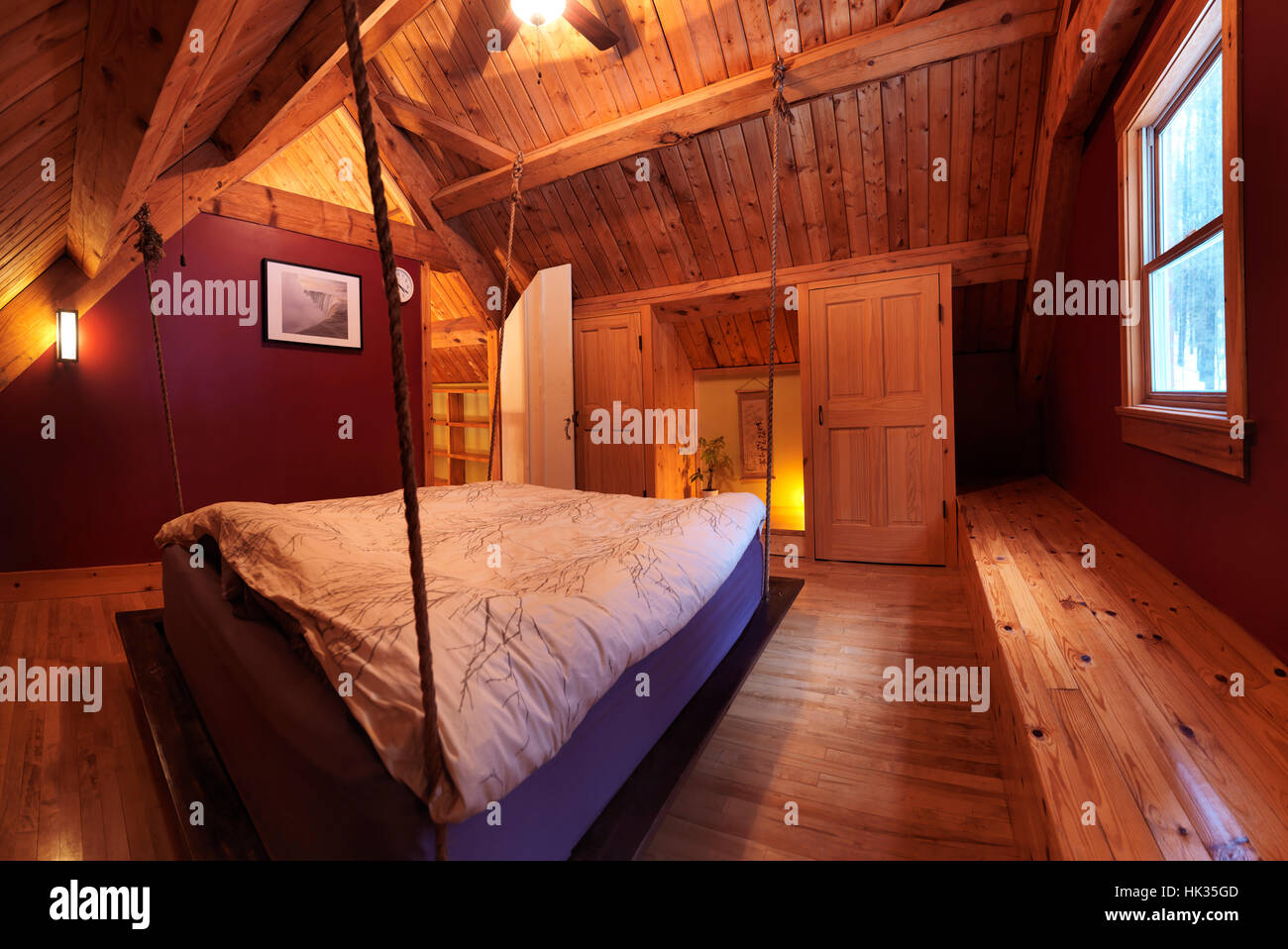 Attic loft bedroom with a hanging bed in a Canadian timberframe country house, interior with a lot of wood, Muskoka, Ontario, Canada Stock Photo