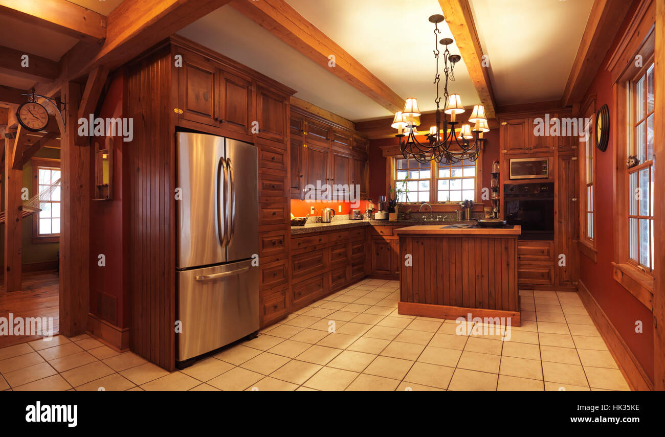 Spacious kitchen interior with lots of wood cabinets and elements in a timberframe Canadian country house in rustic country architectural style, Musko Stock Photo