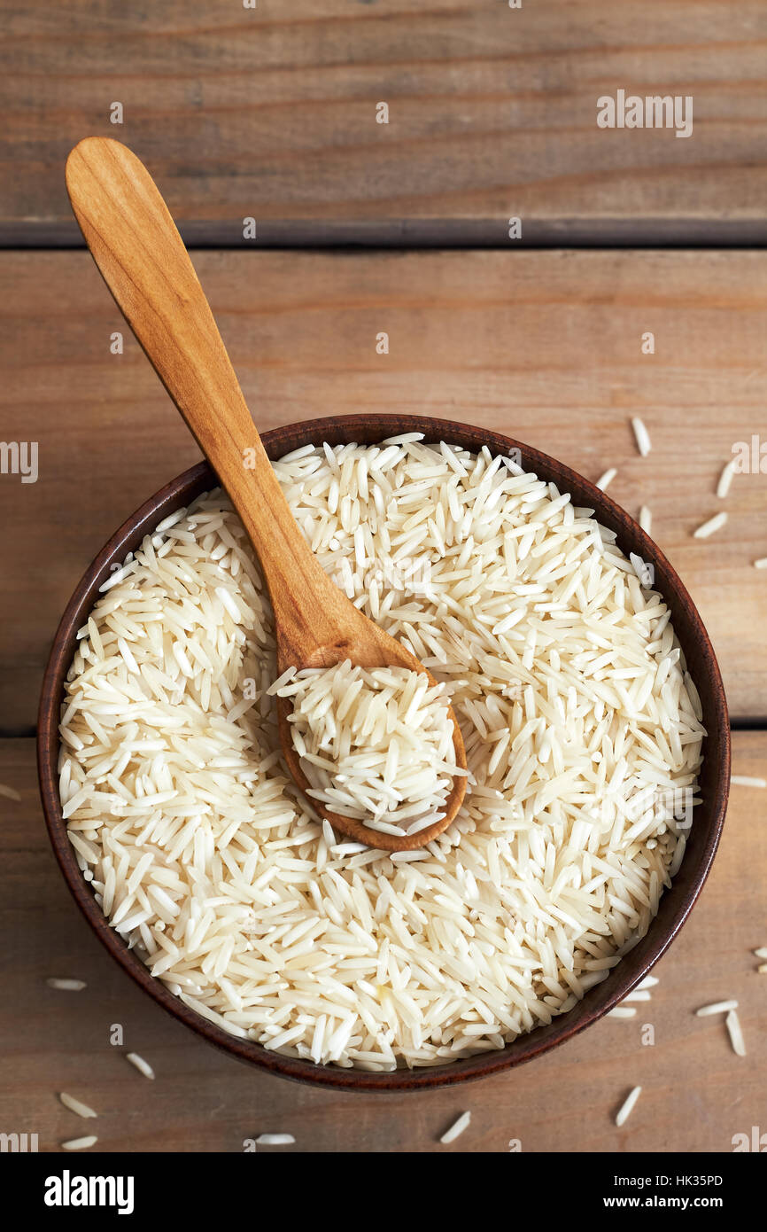 Raw uncooked basmati rice in wooden bowl. Top view with copy space
