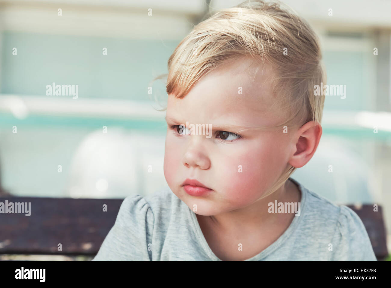 Outdoor close up portrait of serious cute Caucasian blond baby girl ...