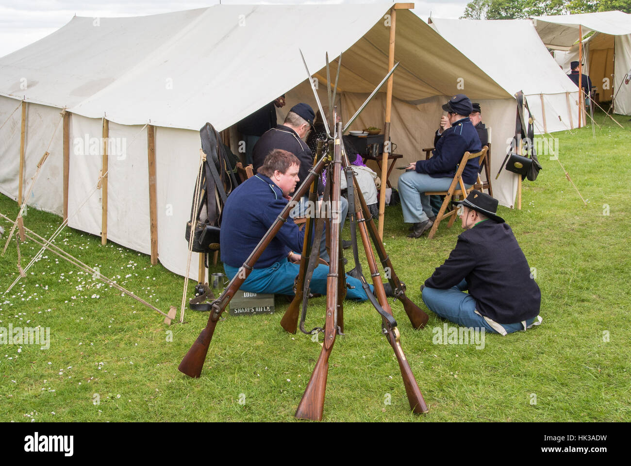 Union solders relax by their tent behind a stack of muskets with bayonets at a reenactment of the America civil war Stock Photo