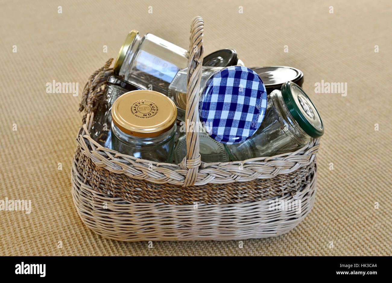 Empty glass jars in vintage wicker basket for reuse in jam making or