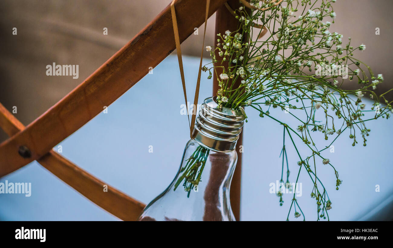 Original wedding floral decoration, minivases and bouquets of flowers hanging from the chair