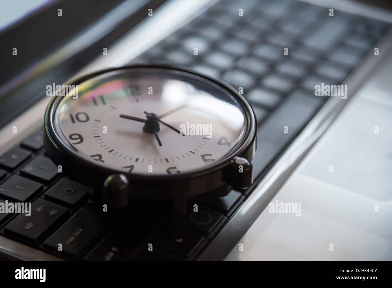 Black clock lay on keyboard time metaphor concept in dark low key tone