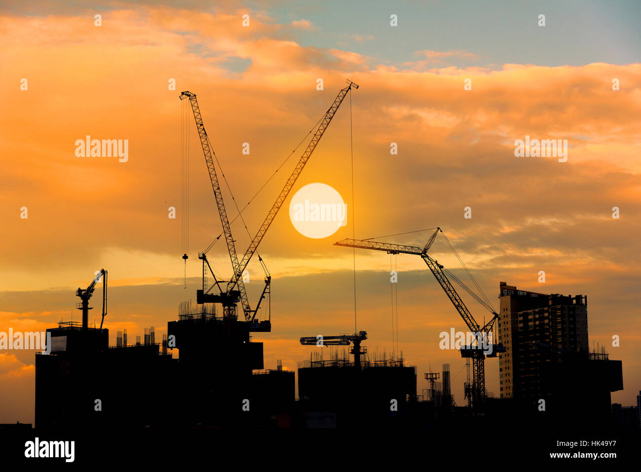 Construction site silhouette on tower building rooftop twilight sunset Stock Photo