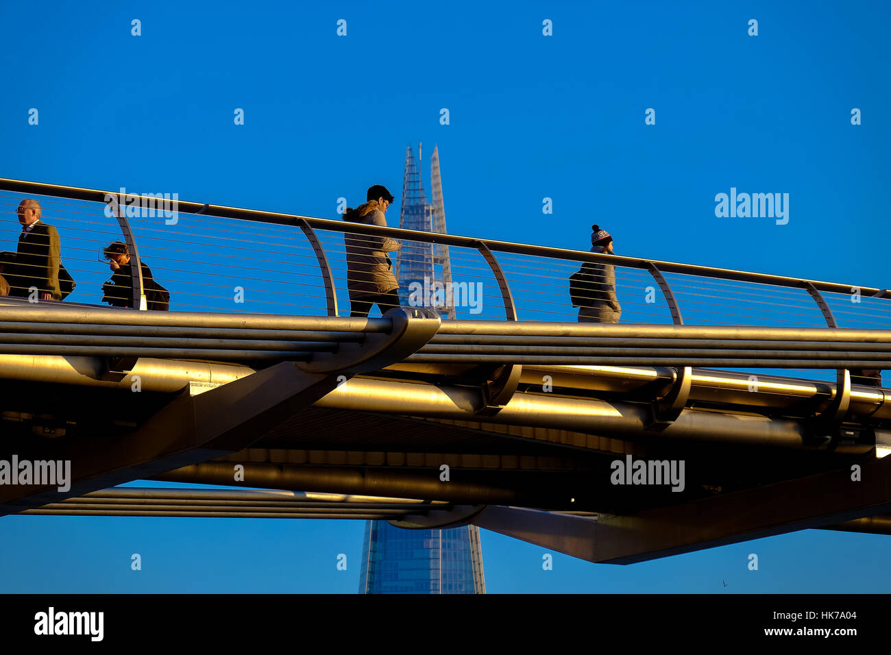 People walk across London's Millennium Bridge with The Shard office building in the background Stock Photo
