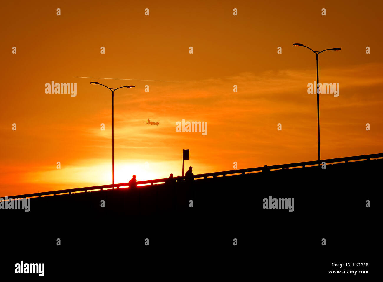 Pedestrians walk across a bridge at sunset Stock Photo