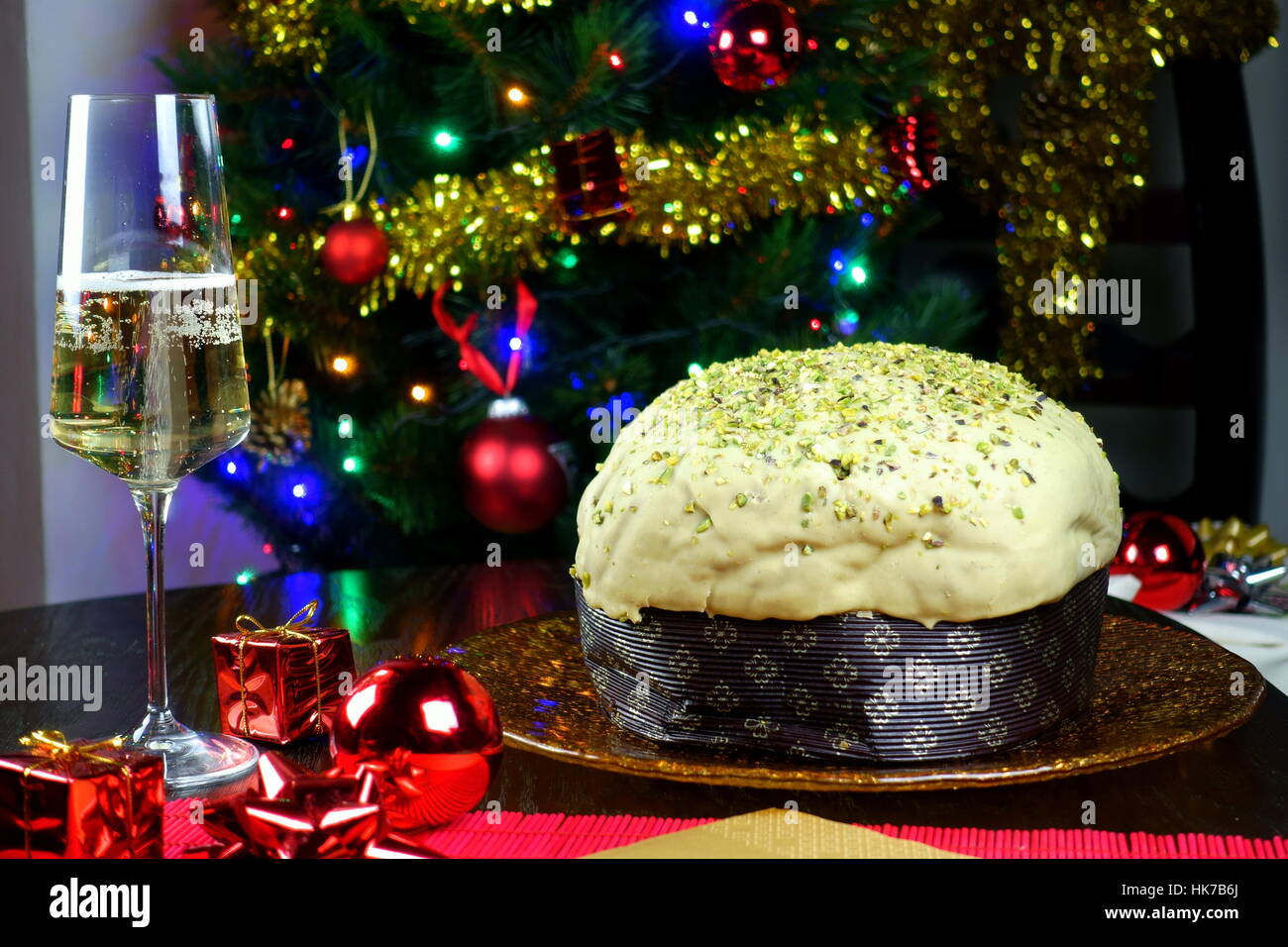 Pistachio panettone, warm hygge atmosphere - Typical Italian Christmas cake with glass of sparkling prosecco and Christmas tree in background Stock Photo