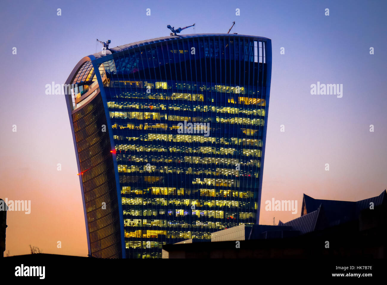 A futuristic looking office building towers above its neighbours in the setting sun Stock Photo