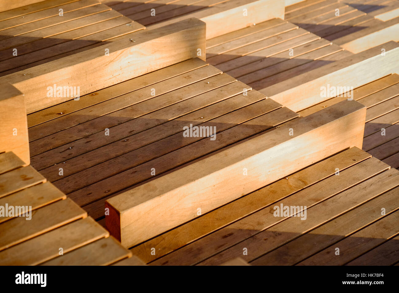 A series of wooden seats cast shadows in the setting sun Stock Photo
