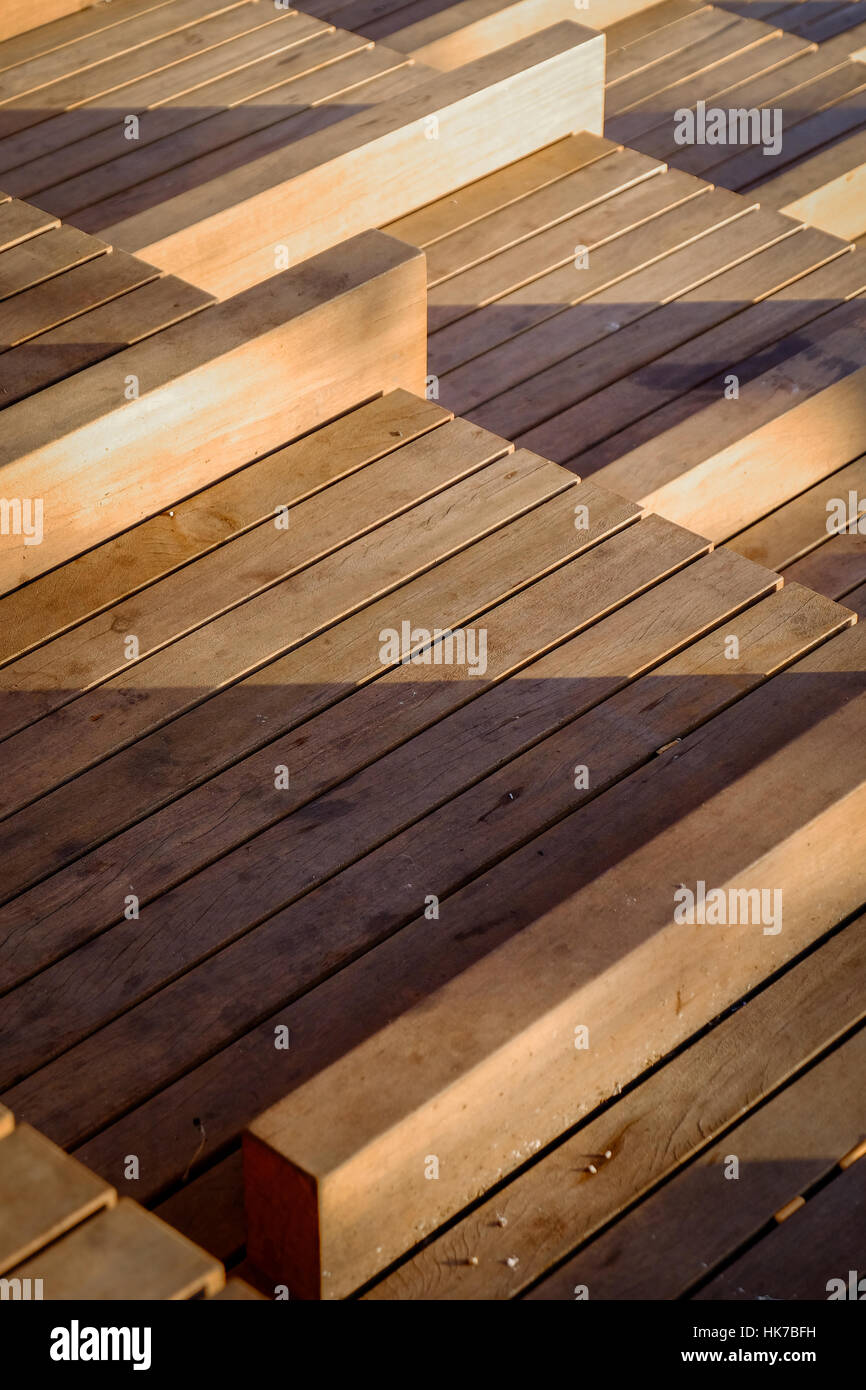 A series of wooden seats cast shadows in the setting sun Stock Photo