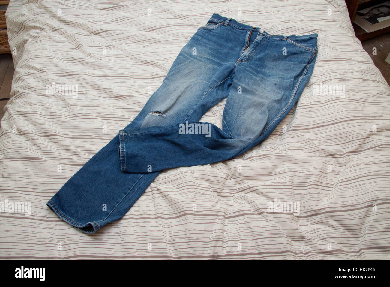 Worn blue jeans on a bed quilt Stock Photo
