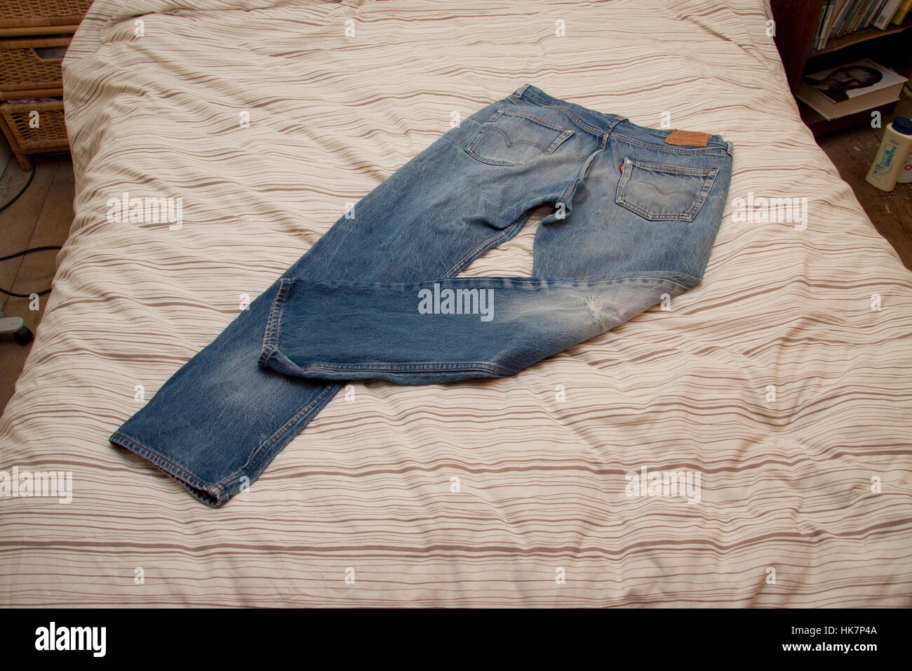 Worn blue jeans on a bed quilt Stock Photo