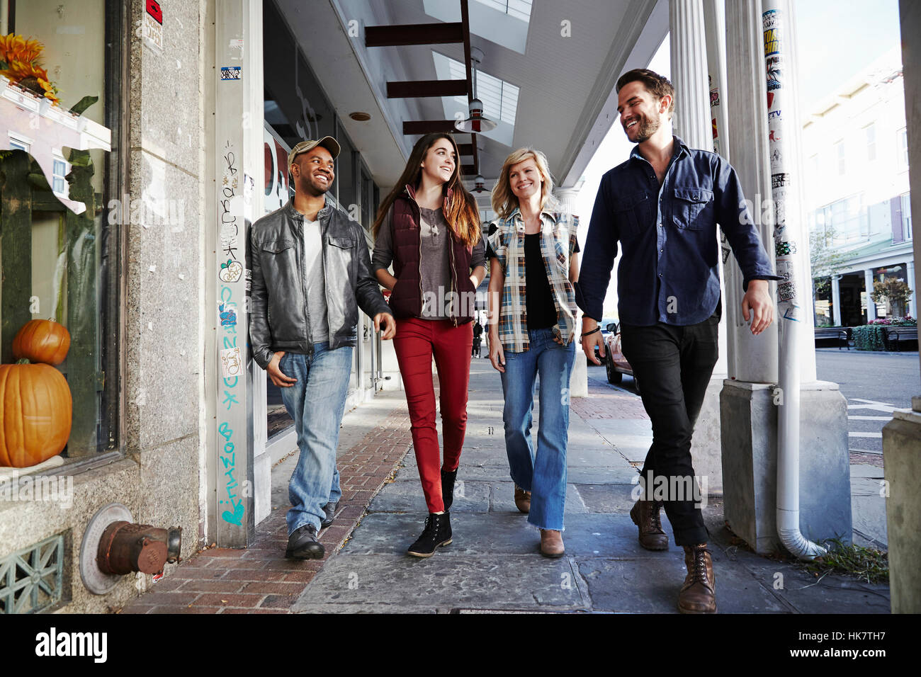 Two young men and two young women walking along a sidewalk, smiling. Stock Photo