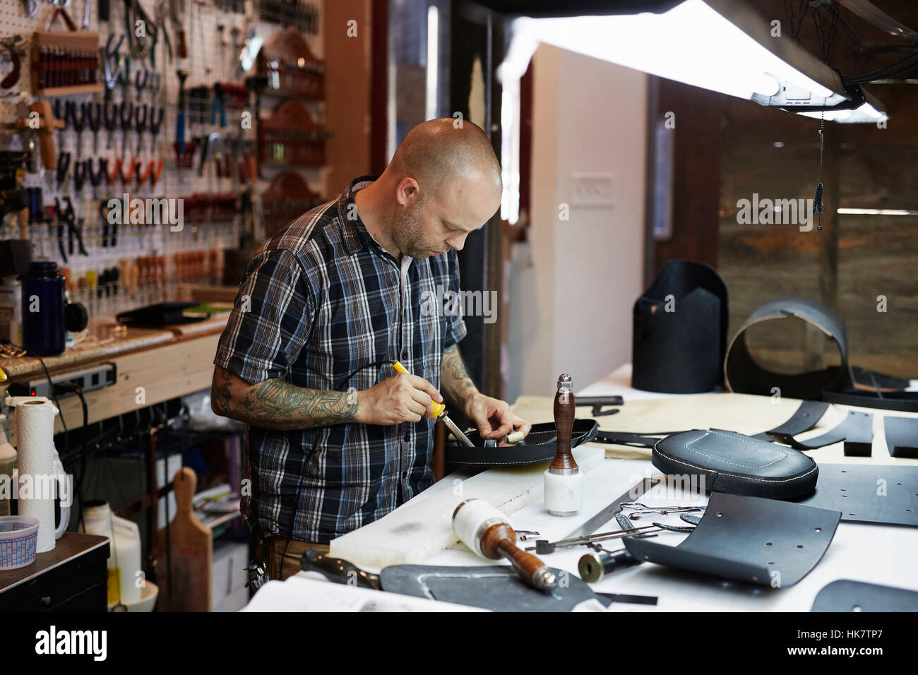 A man working at a bench under a bright light in a leather A