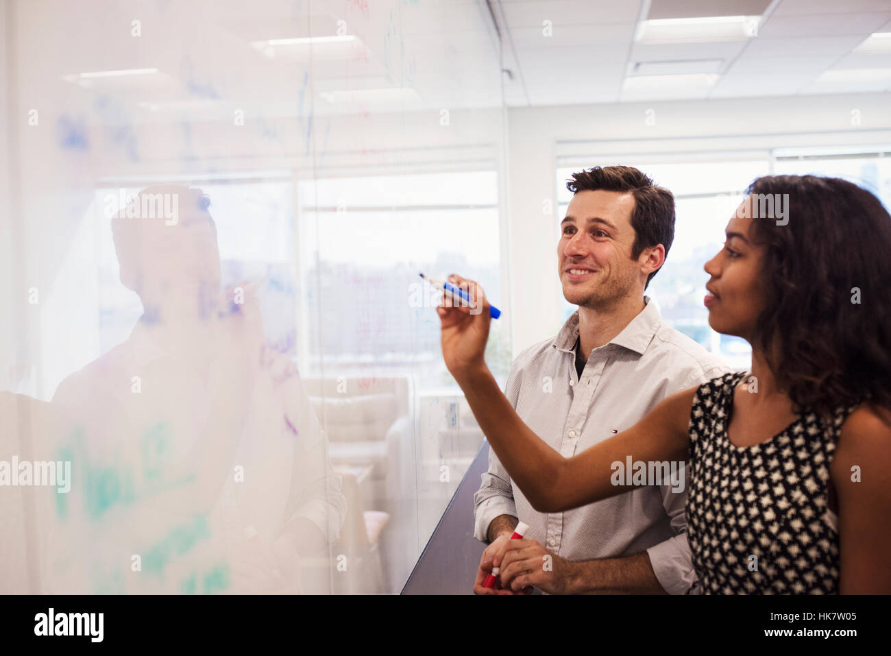 A man and a woman standing in a classroom in front of a whiteboard. Stock Photo