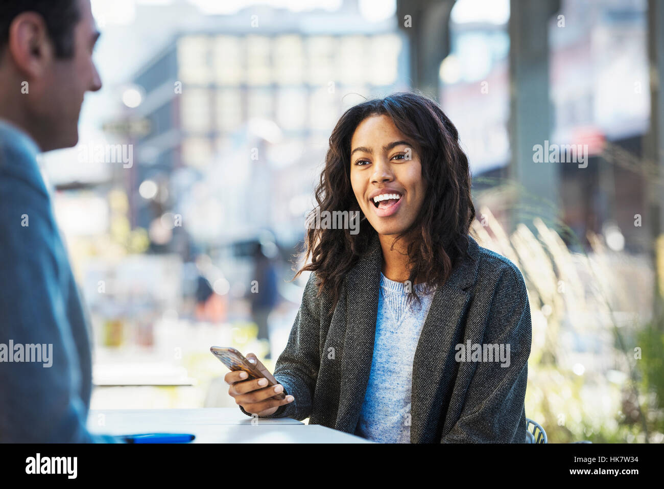 A woman holding a mobile phone, talking to a man on a city street Stock ...