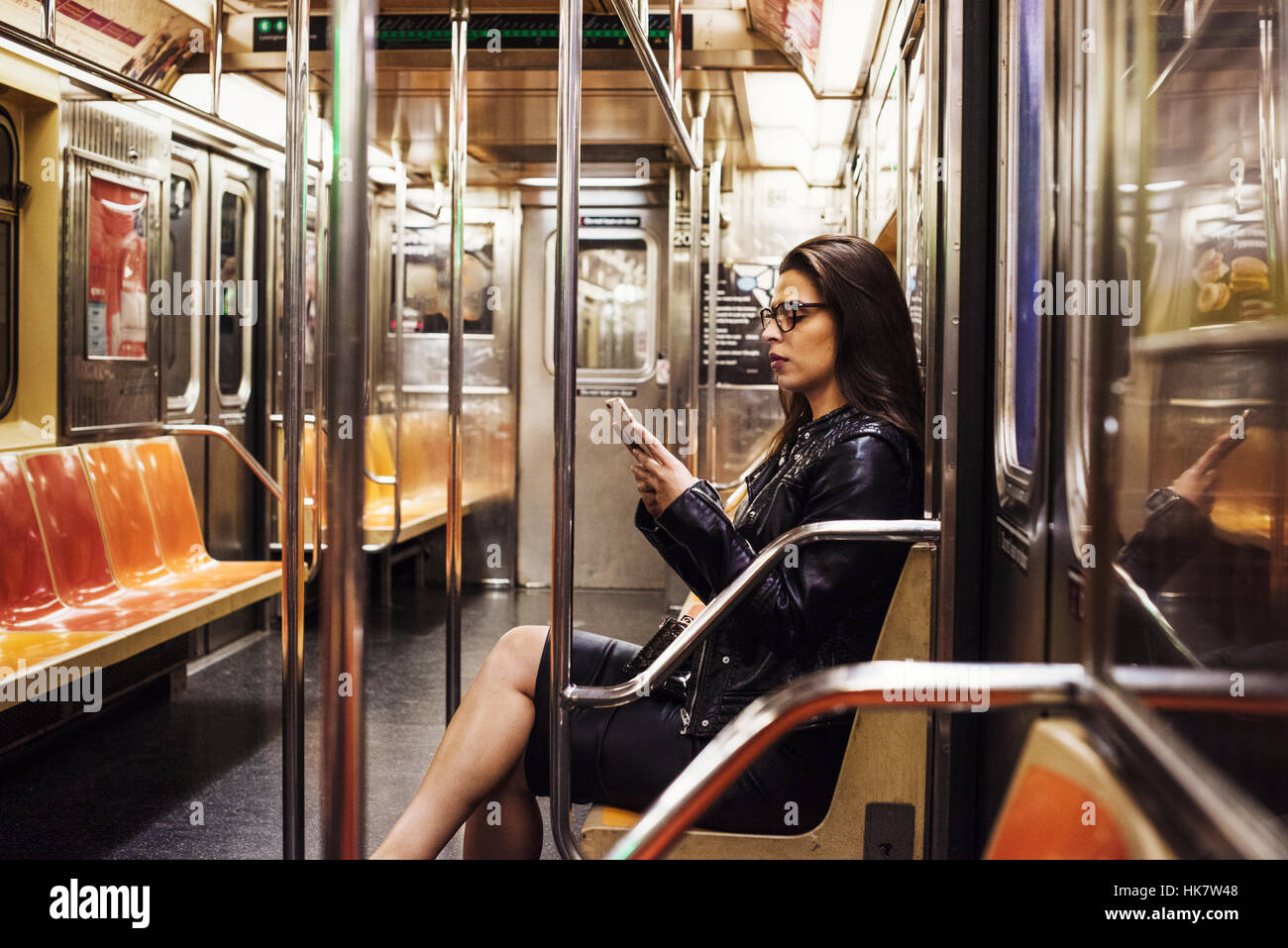 A woman sitting in a metro subway carriage looking at her cellphone