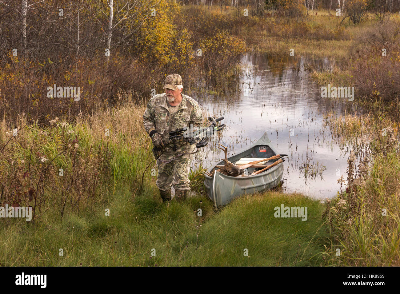 Successful bowhunter returning, in a canoe, with his 8-point buck. Stock Photo