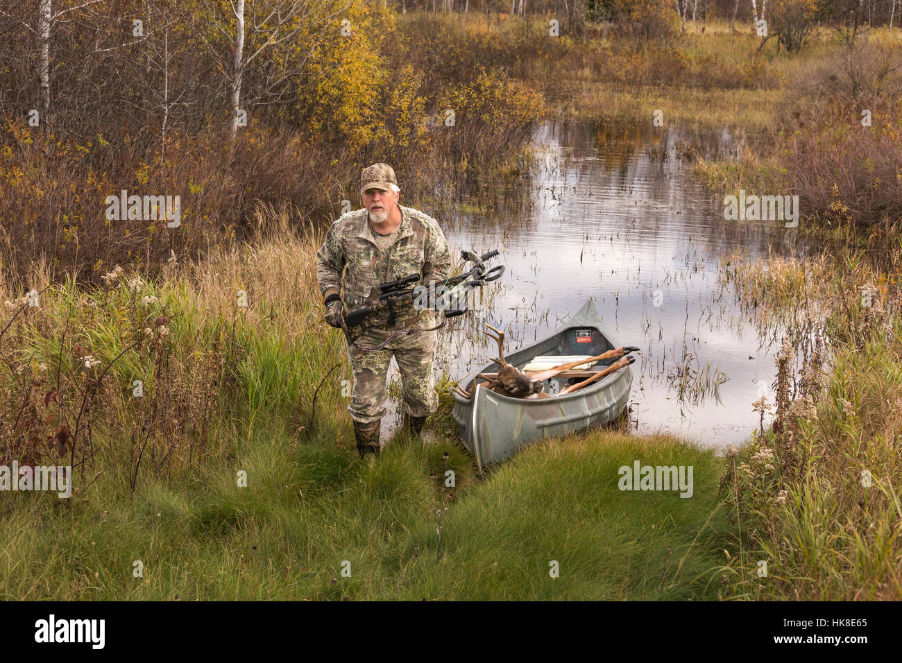 Successful bowhunter returning, in a canoe, with his 8-point buck. Stock Photo