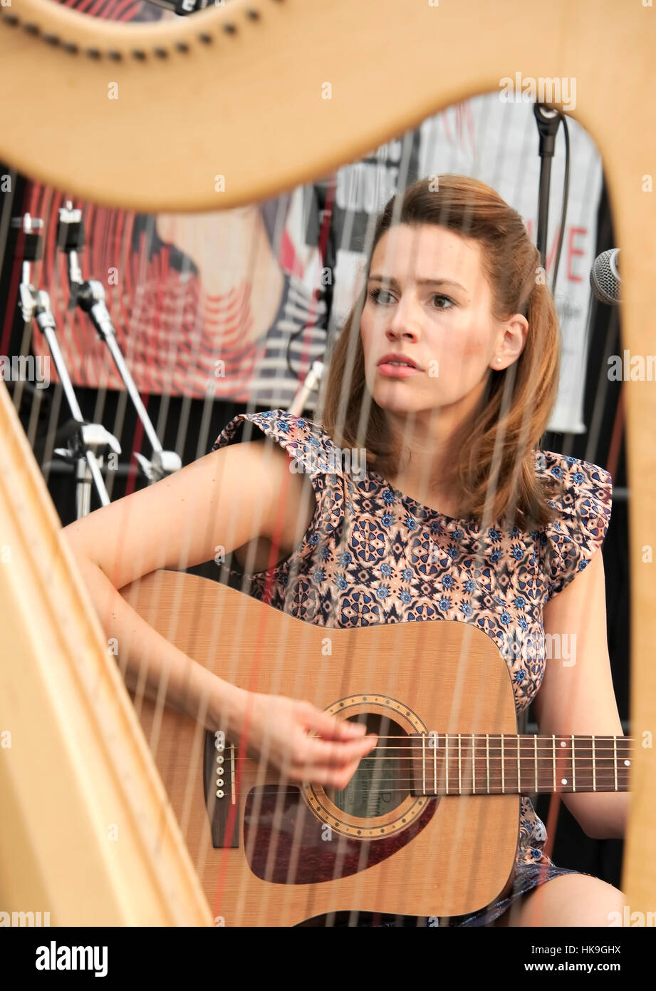Sophie of the group Huradal playing guitar as seen through the harp. Stock Photo