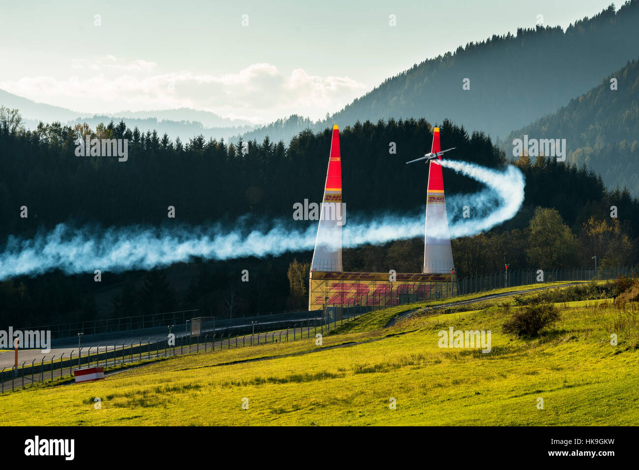 A stunt flying aeroplane, releasing smoke, is flying through 2 pylons ...