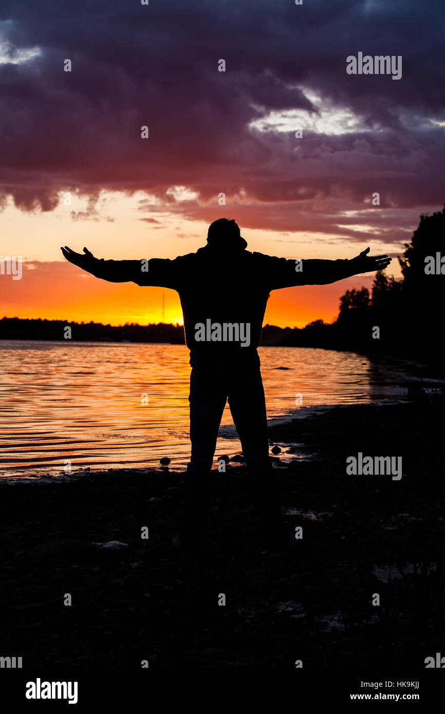 Silhouette of Man Raising His Hands or Open arms when sun rising up Stock Photo