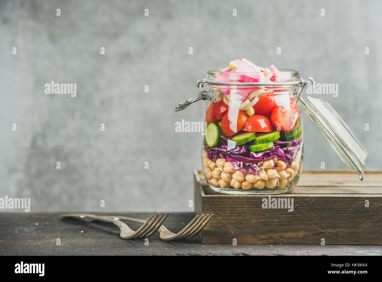 Healthy take-away lunch jar. Vegetable and chickpea sprout vegan salad in glass jar, grey concrete wall background, copy space, selective focus. Clean Stock Photo