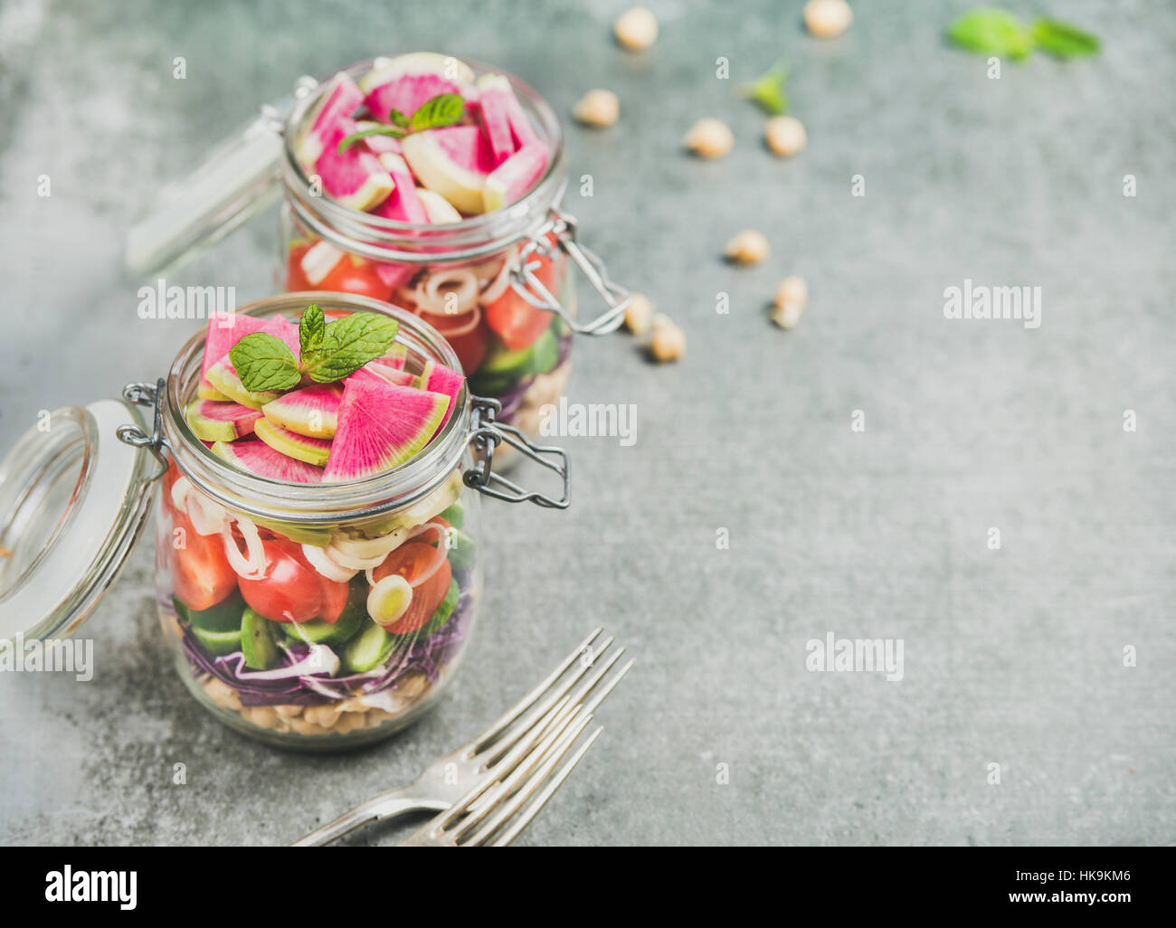 Healthy takeaway lunch jars. Vegetable and chickpea sprout layered vegan salad in glass jars