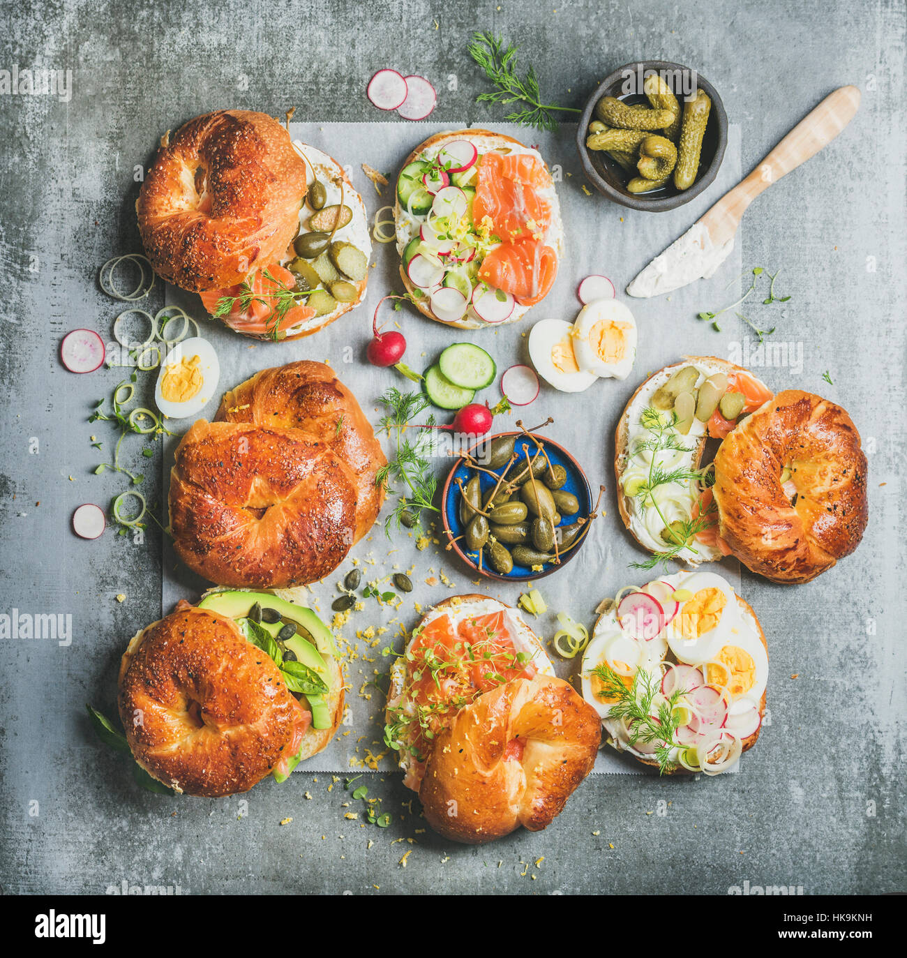Variety of bagels with smoked salmon, eggs, radish, avocado, cucumber, greens and cream cheese for breakfast, healthy lunch or party over grey concret Stock Photo