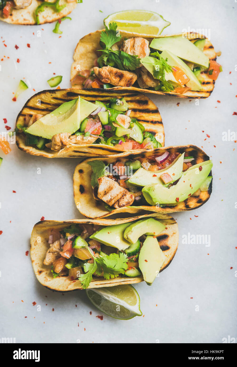 Healthy corn tortillas with grilled chicken fillet, avocado, fresh salsa, limes over light grey marble background, top view. Healthy food, gluten-free Stock Photo