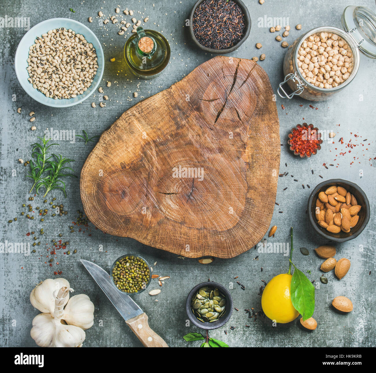 Ingredients for healthy cooking. Variety of beans, black rice, chickpeas, almonds, seeds, herbs, spices and olive oil over grey concrete textured back Stock Photo