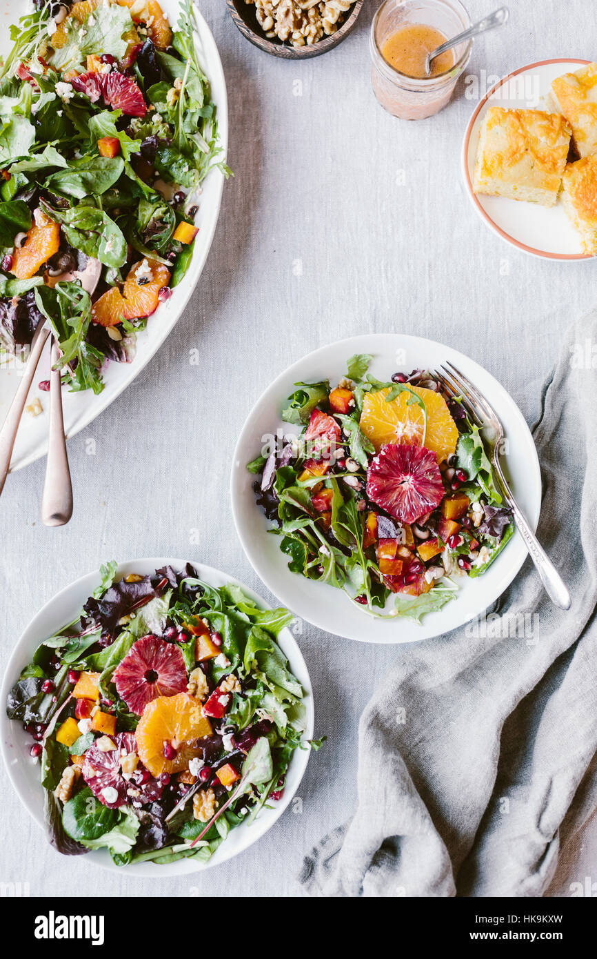 Bowls of Citrusy Roasted Beet Goat Cheese Salad with Black Eyed Peas are photographed from the top with cornbread on the side. Stock Photo