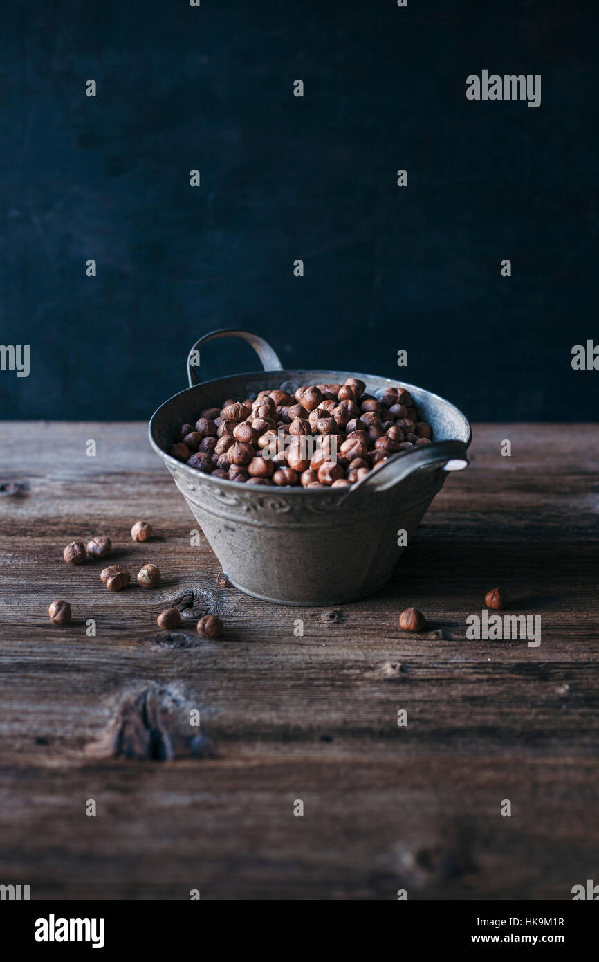 Raw hazelnuts in a metal bucket on a wooden table Stock Photo